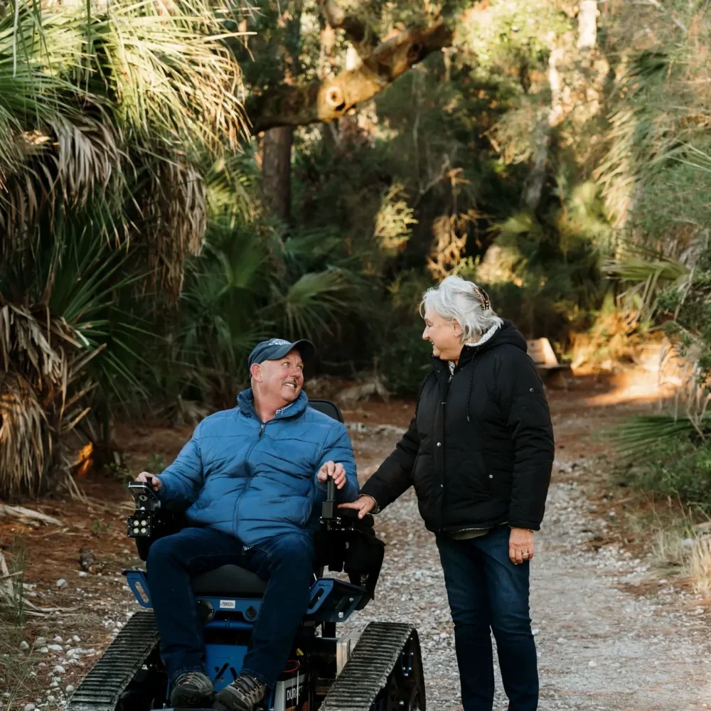 A man in the Action Trackchair AXIS poses with a female on a pathway in a park